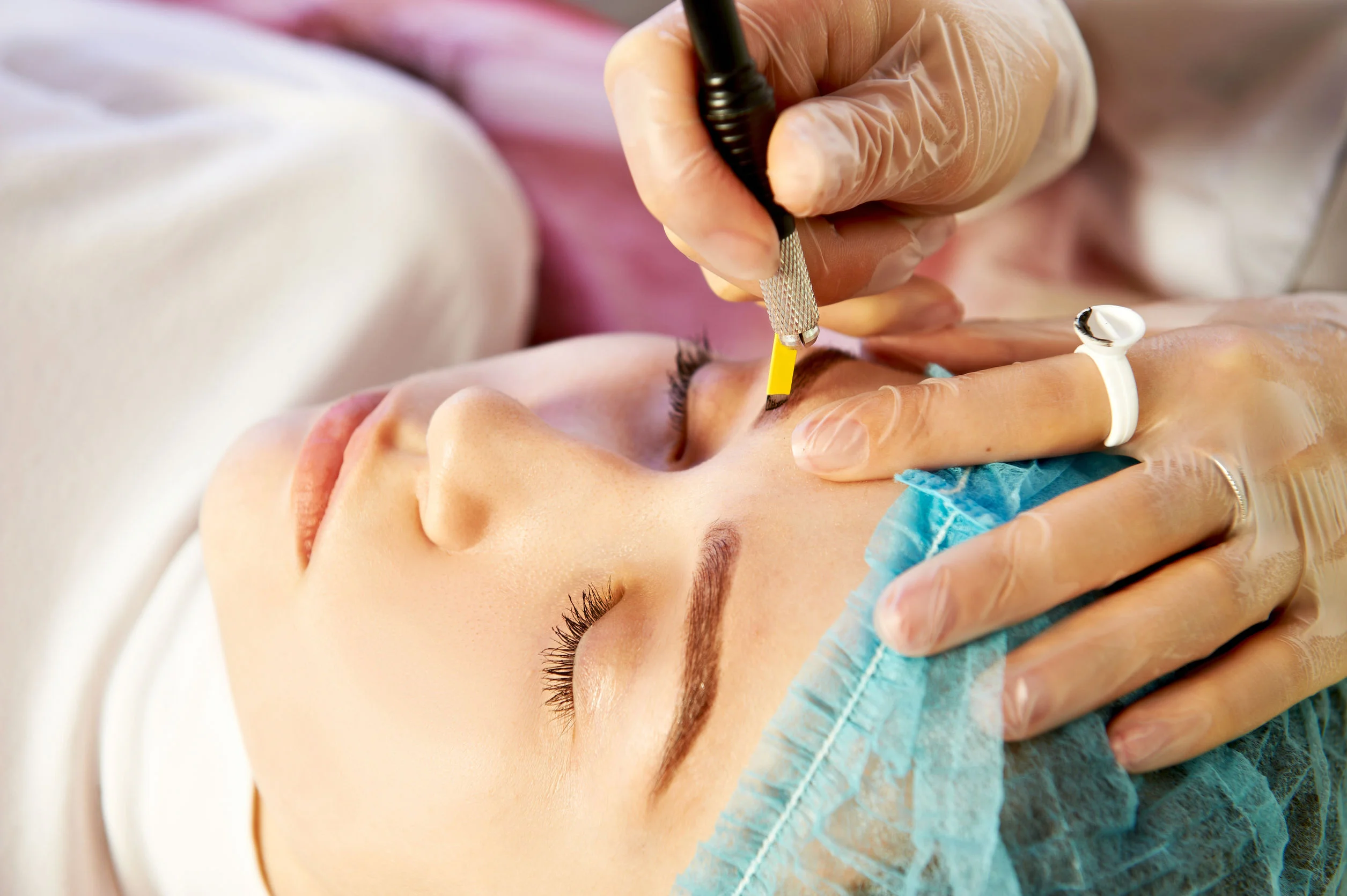 61906892 - cosmetician making permanent eyebrow make up for beautiful girl. eyebrow tattoo. close up.